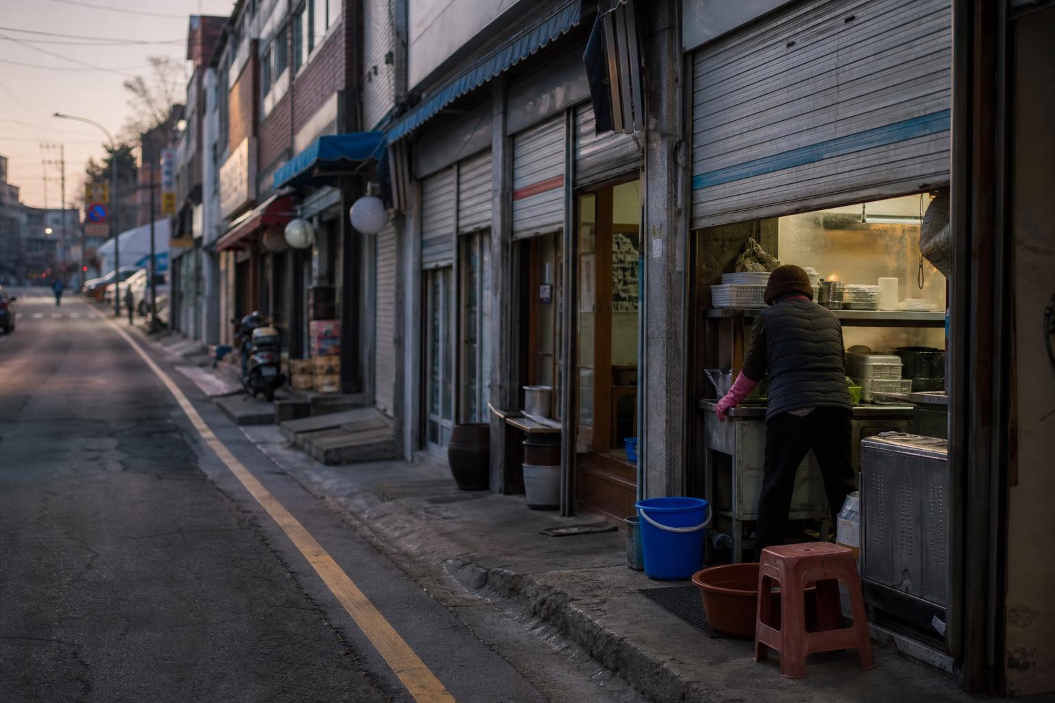 이른 아침 문을 열기 전 셔터가 반쯤 올라간 한국의 골목 상점가